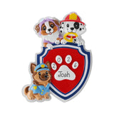 A Paw Patrol-themed personalized dog plaque featuring Marshall, Rubble, and Chase around a red shield with a white paw print and the name 'Josh' and year '2026'.