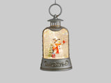 A silver hanging lantern Christmas ornament with a snow globe effect and a snowman figure inside, shown against a light gray background with product text on the right.