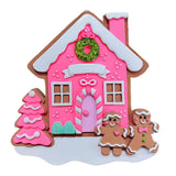 Decorative gingerbread house with pink walls, white roof, and gingerbread men on a white background