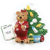 Christmas ornament with a teddy bear in a red dress and baby items on a white background